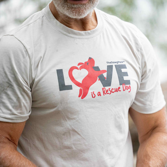 Person wearing a white t-shirt with a graphic and text 'LOVE is a Rescue Dog' outdoors.
