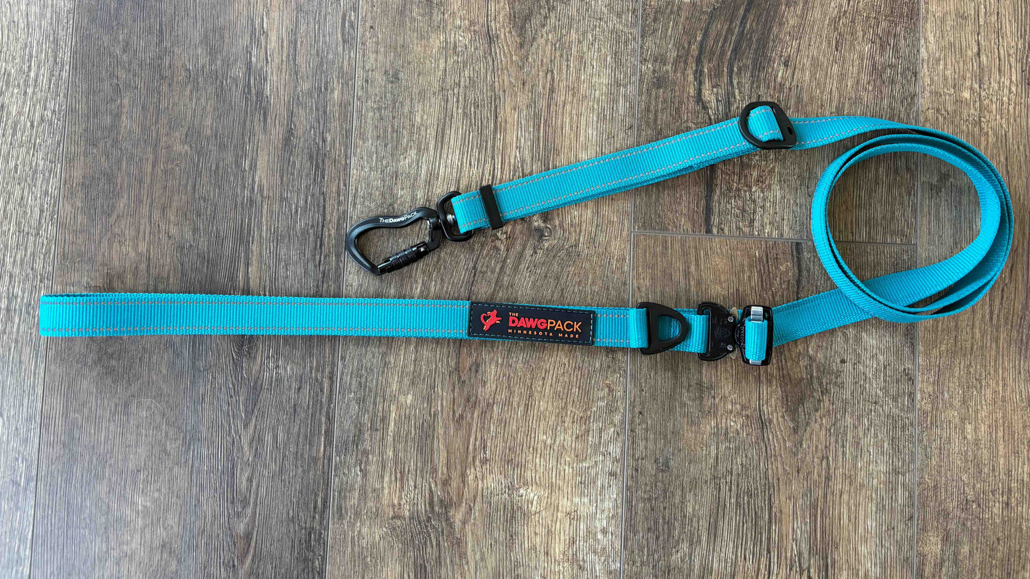 Teal dog leash with a black clip on a wooden surface