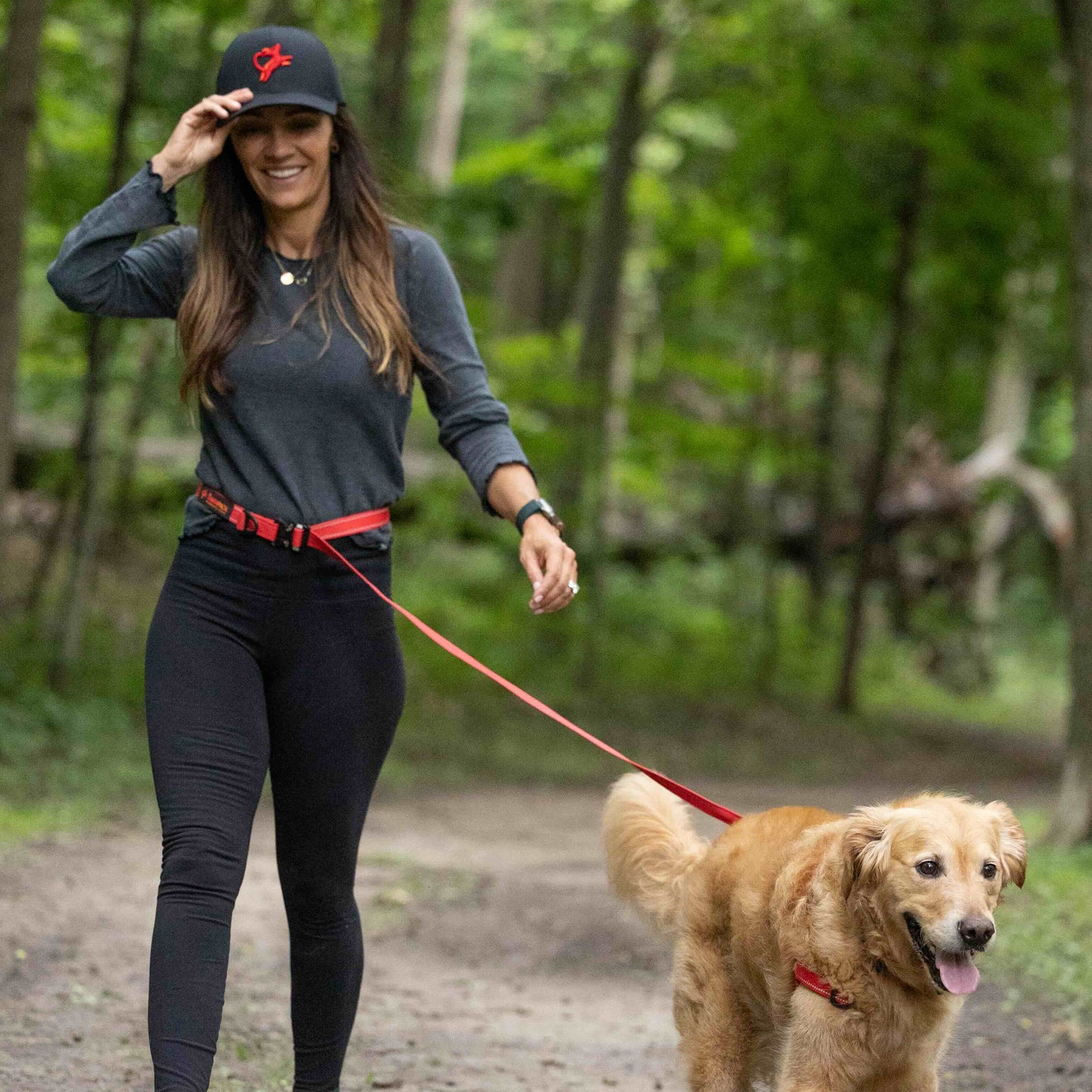 Woman walking a dog on a leash in a forest