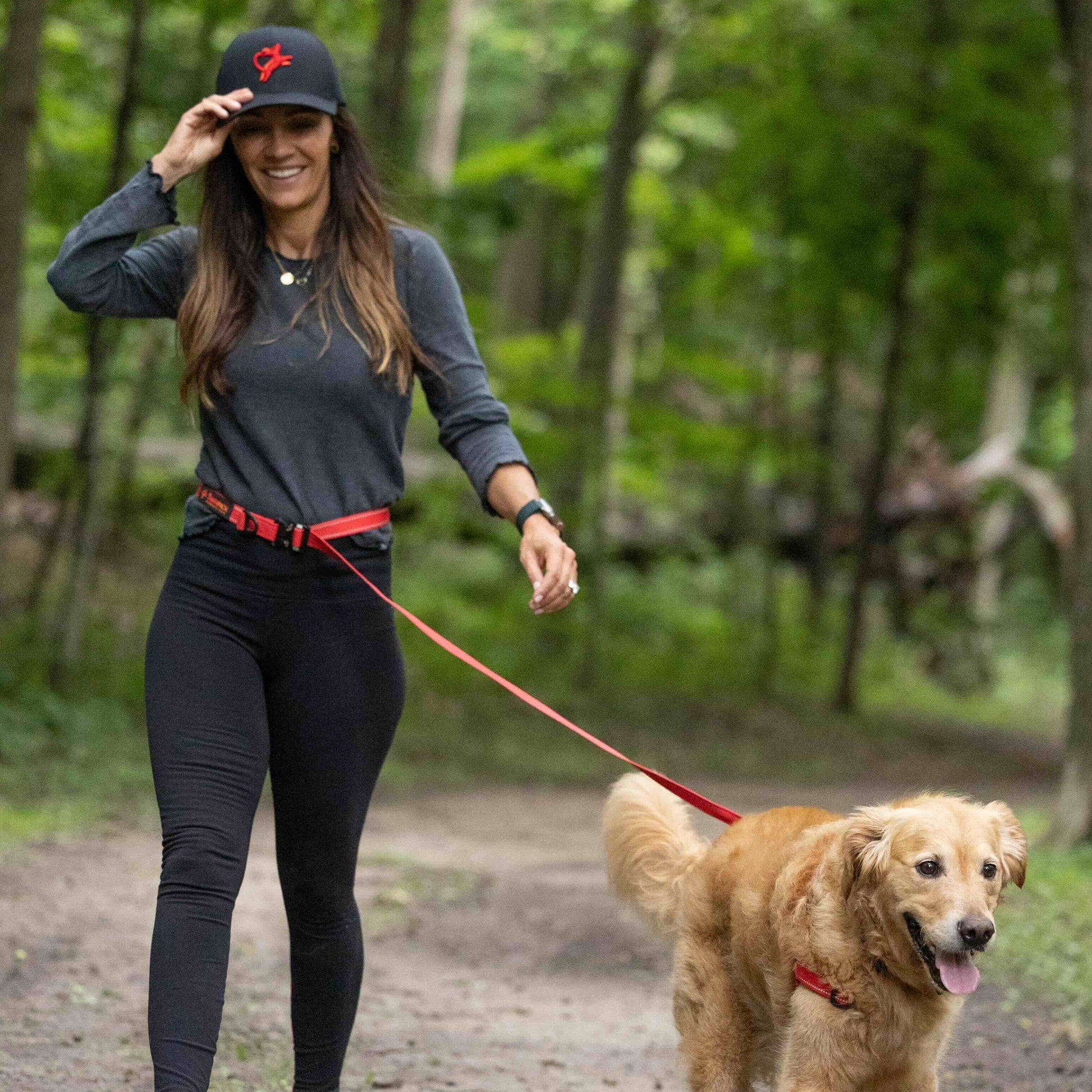 Woman walking a dog on a leash in a forest